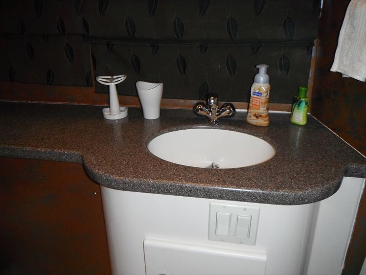 Barely can see the window shade behind the sink and the brown on the wall below the sink.